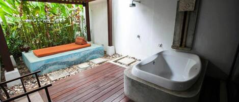 Una terraza de madera con un jacuzzi, un banco y una pequeña mesa.
