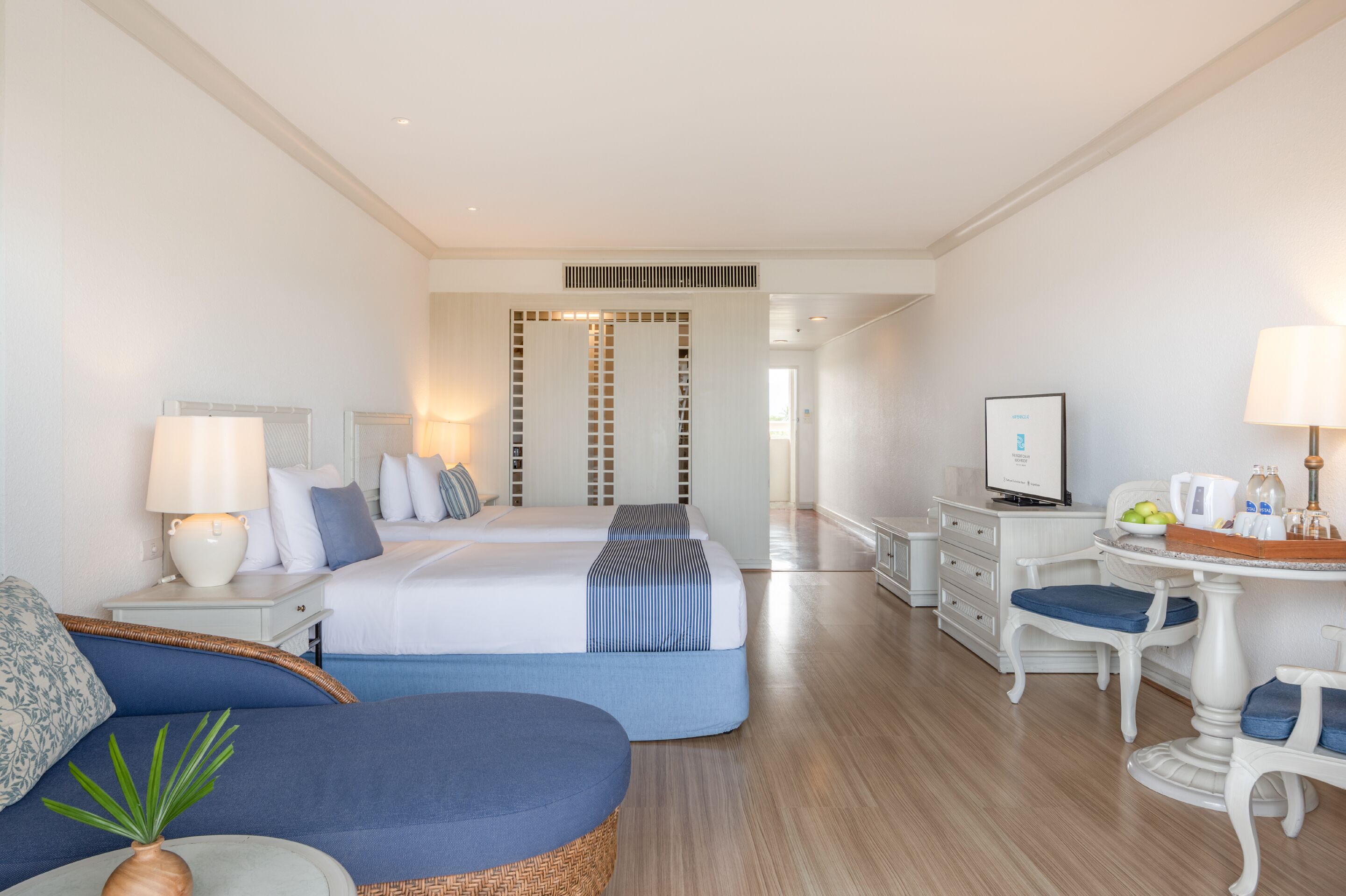 Una habitación de hotel con cama, sofá, escritorio con computadora, silla y lámpara.