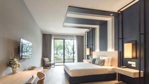 Habitación de hotel moderna con una cama grande, un escritorio y un televisor.