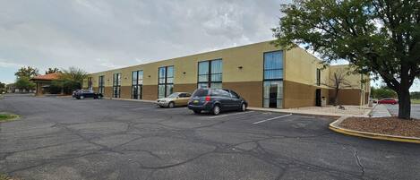 A parking lot with a building that has large windows and a flat roof.