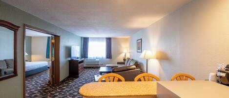 A hotel room with a bed, a desk, a chair, a sofa, and a window with curtains.