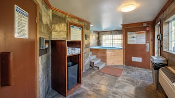 Un cuarto de spa con puerta de madera, un perchero, zona de ducha y un cartel con las normas del spa.