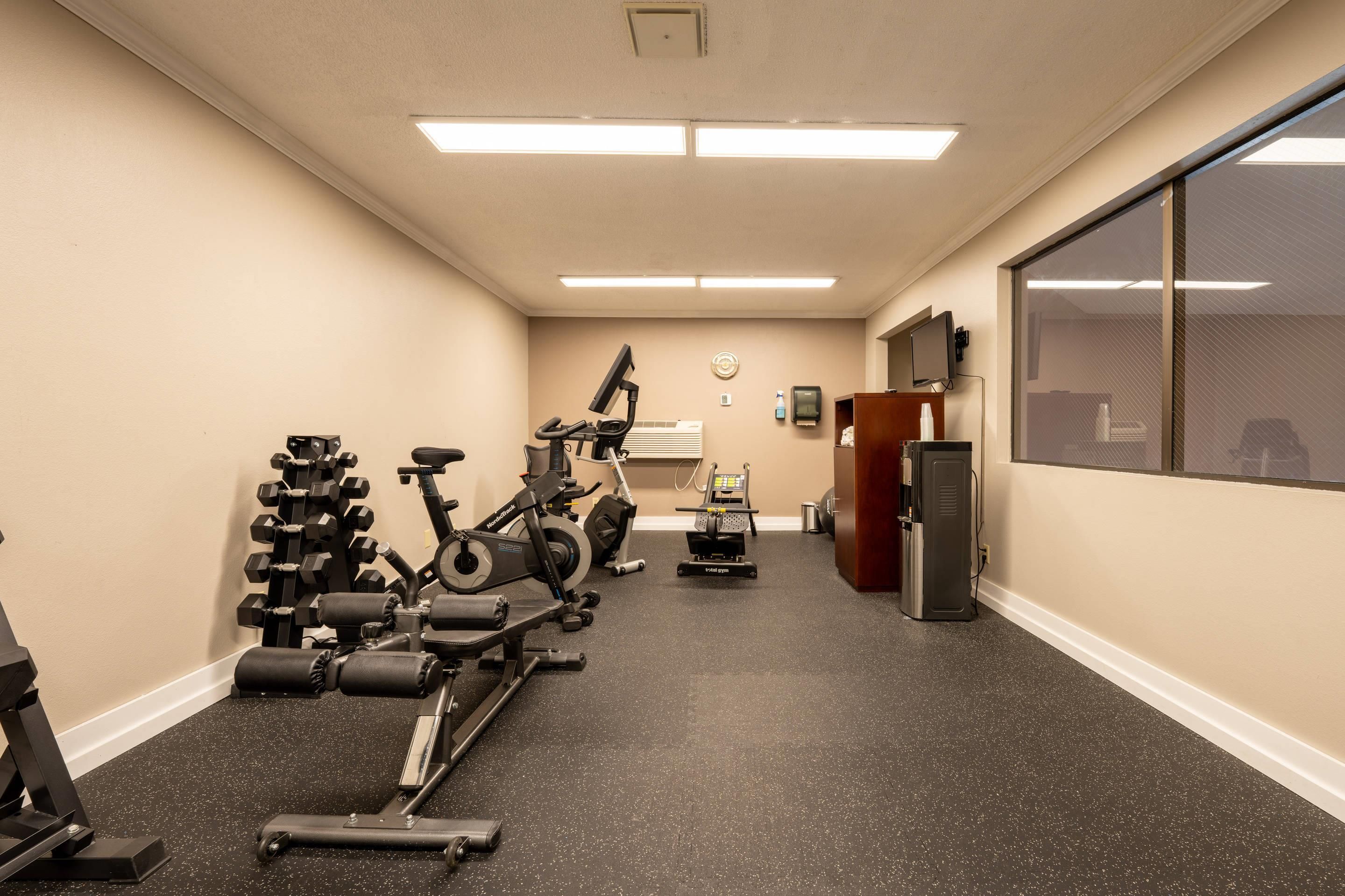 Un gimnasio con equipamiento de ejercicio, una cinta de correr y una bicicleta estática.