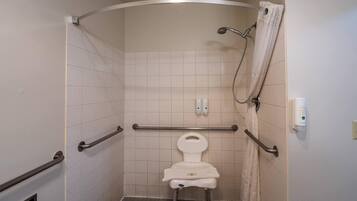 A small, enclosed shower stall with a toilet, grab bars, and a showerhead.