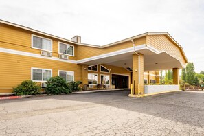 A yellow building with a covered entrance, air conditioning units, and a bench outside. - Quality Inn Paradise Creek Pullman (Pullman)