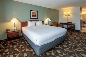 A hotel room with a large bed, two bedside tables with lamps, a chair, a desk, and a bathroom visible through an open door. - Quality Inn Paradise Creek Pullman (Pullman)