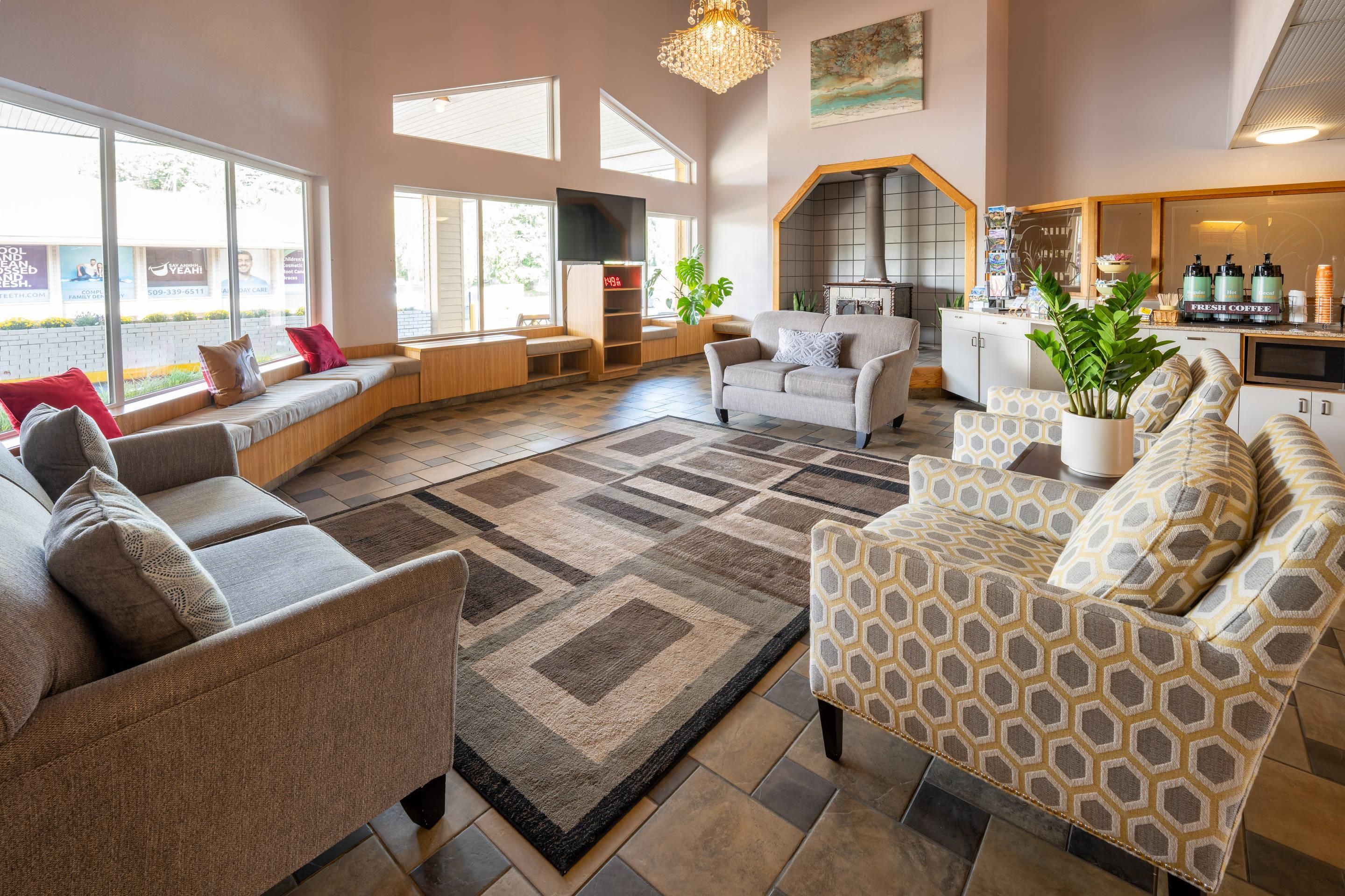 A spacious living area with a sofa set, a patterned armchair, and a coffee station.