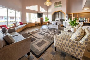 Amplia sala de estar con un conjunto de sofás, un sillón estampado y una estación para café.