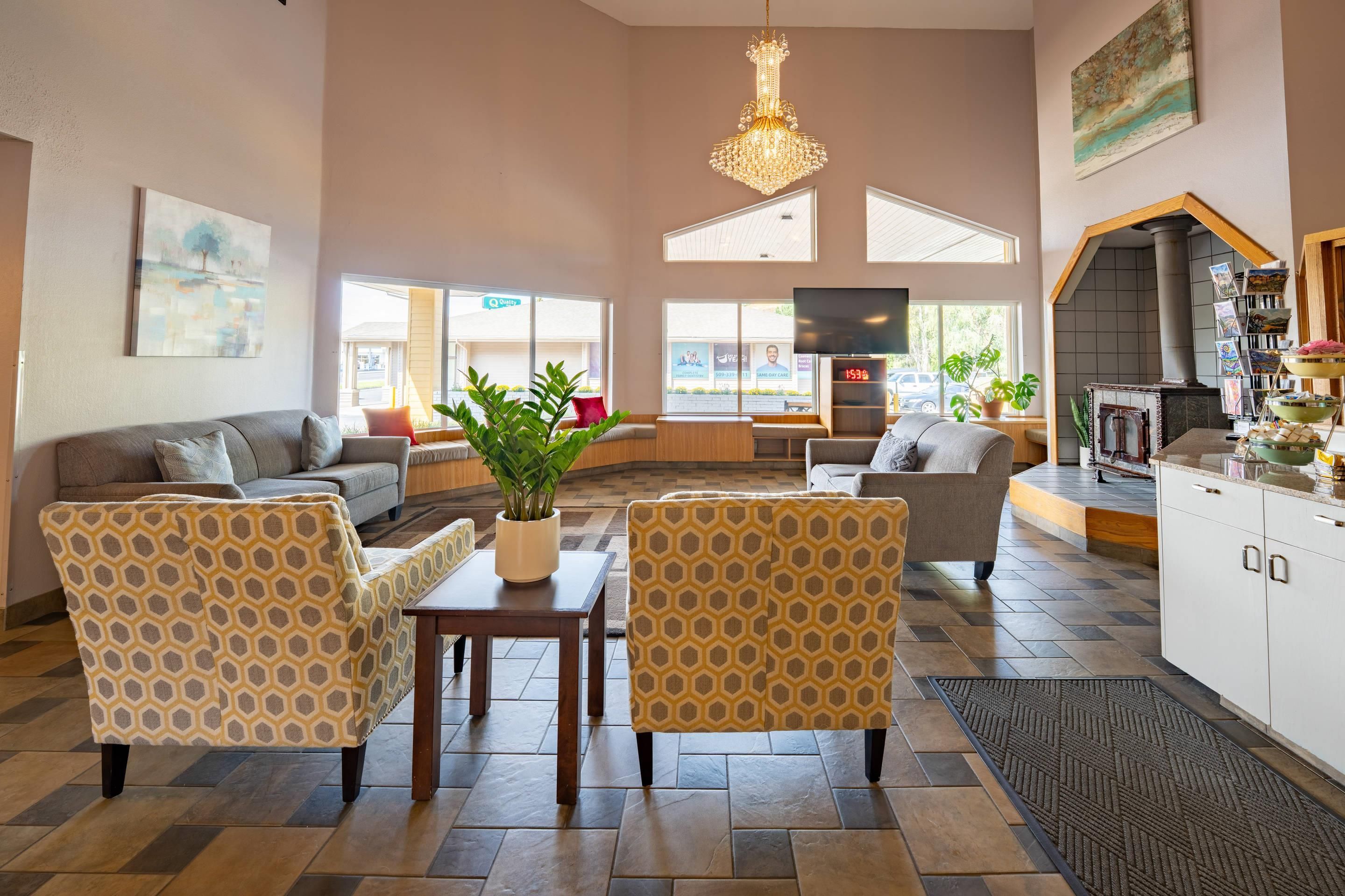 Een ruime woonkamer met een bank, fauteuils, een salontafel en een televisie. Er is een keuken met een fornuis en een eettafel.