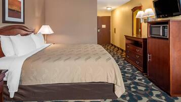 A hotel room with a bed, a desk, a television, and a microwave.