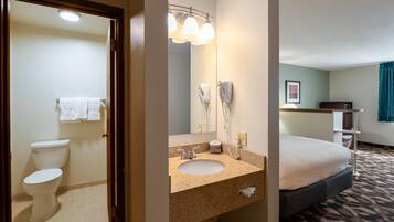 A hotel bathroom with a toilet, sink, and mirror.