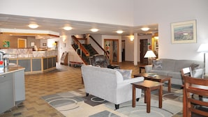 A spacious living area with a kitchen, a grey sofa, a wooden coffee table, and a staircase leading to another level.