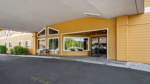 Un hotel con entrada techada, ventanas amplias y un banco en el exterior.