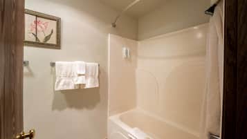 A bathroom with a bathtub, a towel rack with two towels, a framed picture on the wall, and a shower curtain.