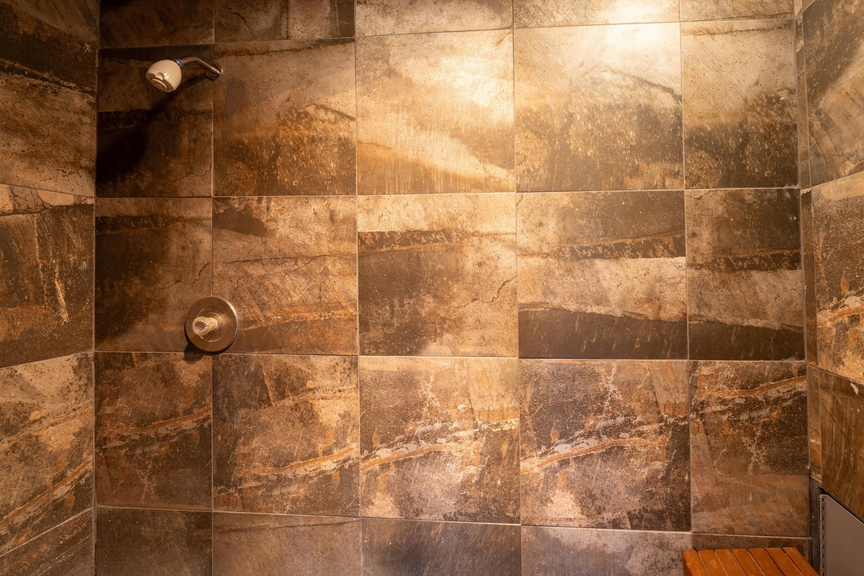 A shower area with a tiled wall and a showerhead.