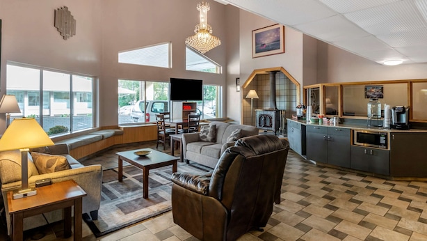 A spacious living area with a sofa, armchair, and coffee table, a fireplace, and a kitchen counter with appliances.