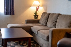 A living room with a sofa, a wooden coffee table, and a floor lamp with a plant. - Quality Inn Paradise Creek Pullman (Pullman)
