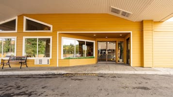Un edificio amarillo con amplias ventanas y un banco en el exterior.