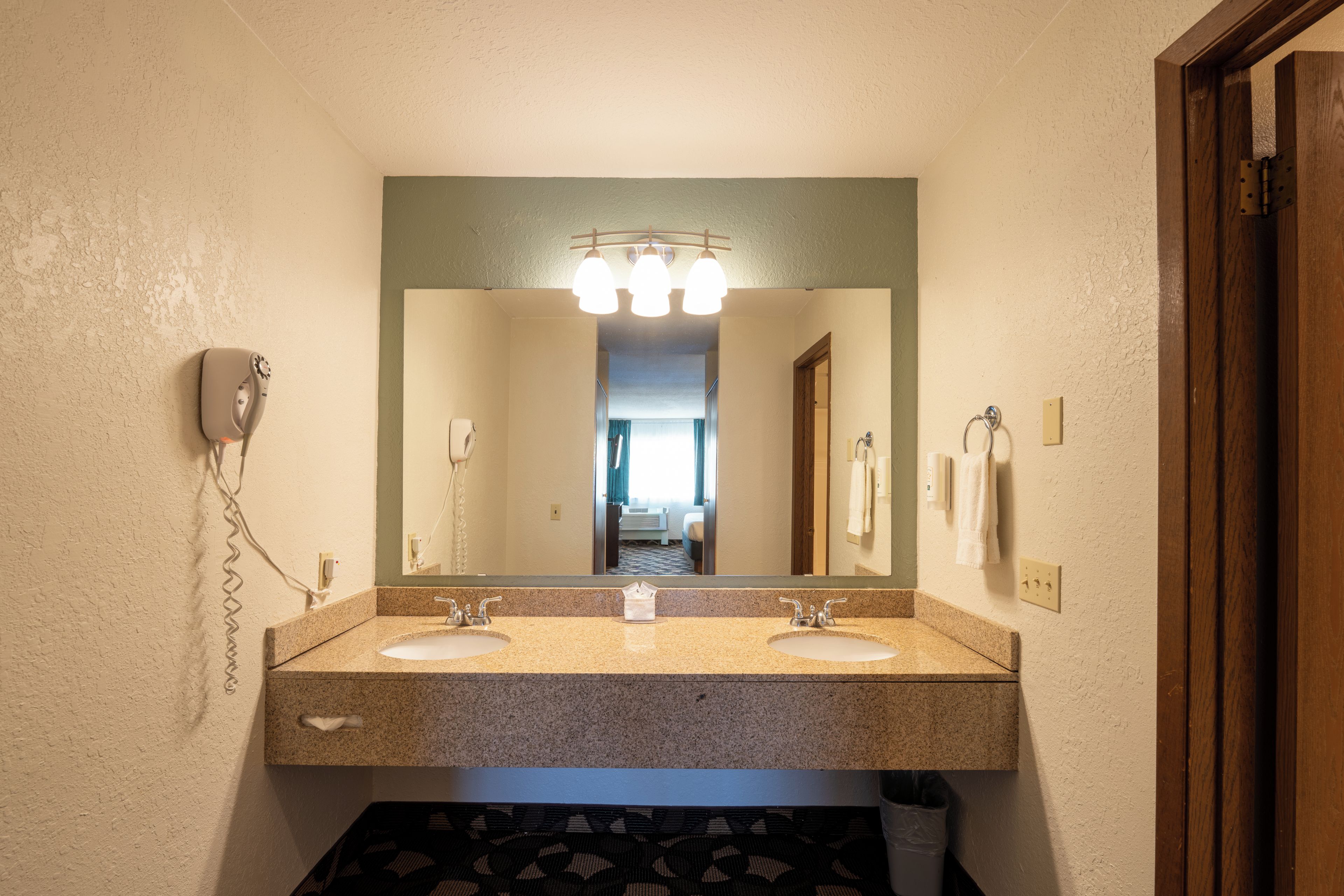 Een badkamer met twee wastafels, een haardroger en een spiegel.