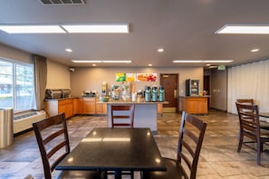 A spacious hotel kitchen with a central island, wooden chairs, and a dining table. - Quality Inn Paradise Creek Pullman (Pullman)