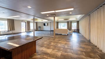 A spacious hotel lobby with a marble reception desk, large windows, and a flat-screen TV mounted on the wall.