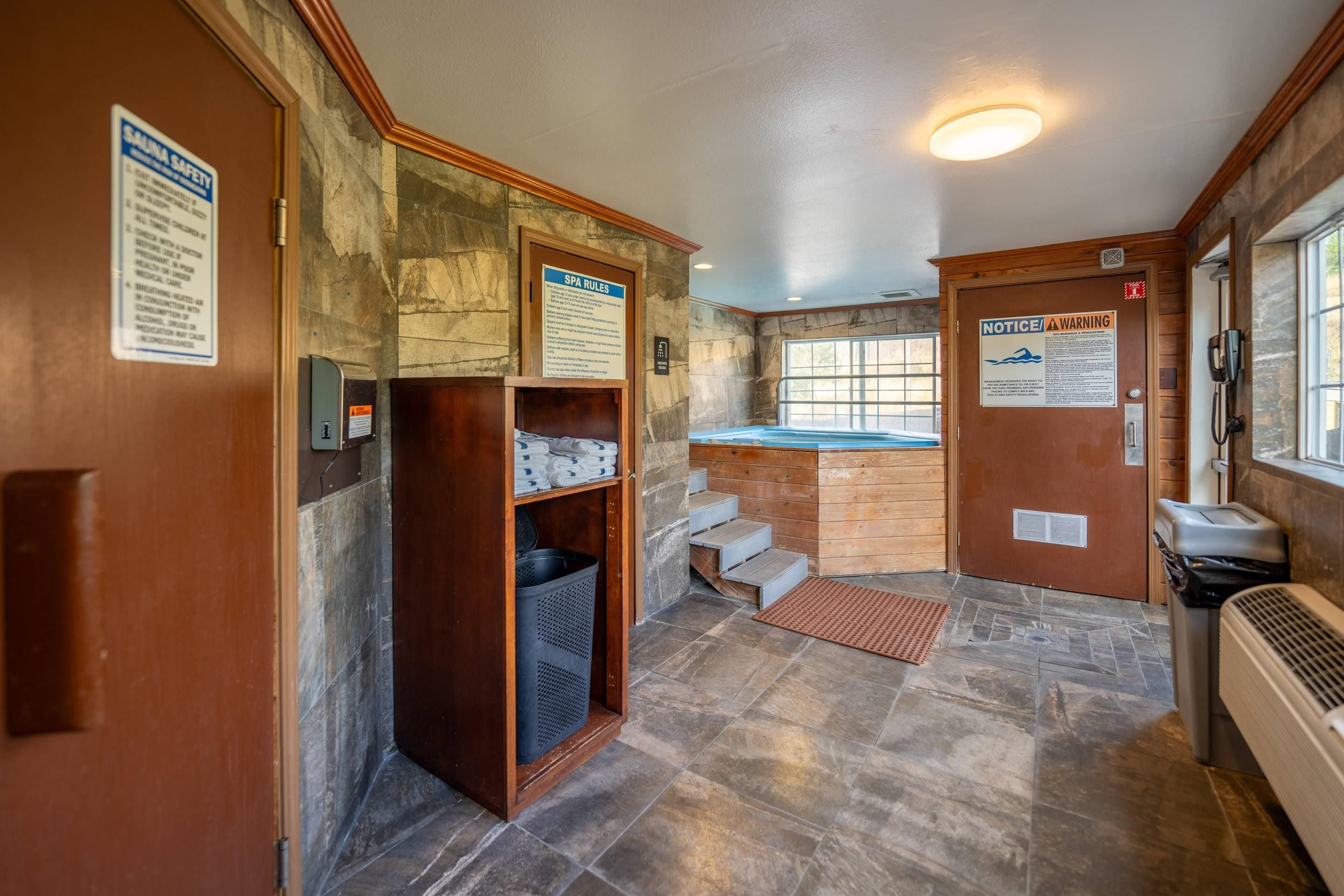 Un cuarto de spa con un banco de madera, un perchero para toallas y un letrero que indica las normas del spa.