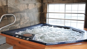 A hot tub with a wooden bench, stone walls, and a window with a view.