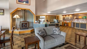 A cozy hotel lobby with a fireplace, seating area, and a reception desk.