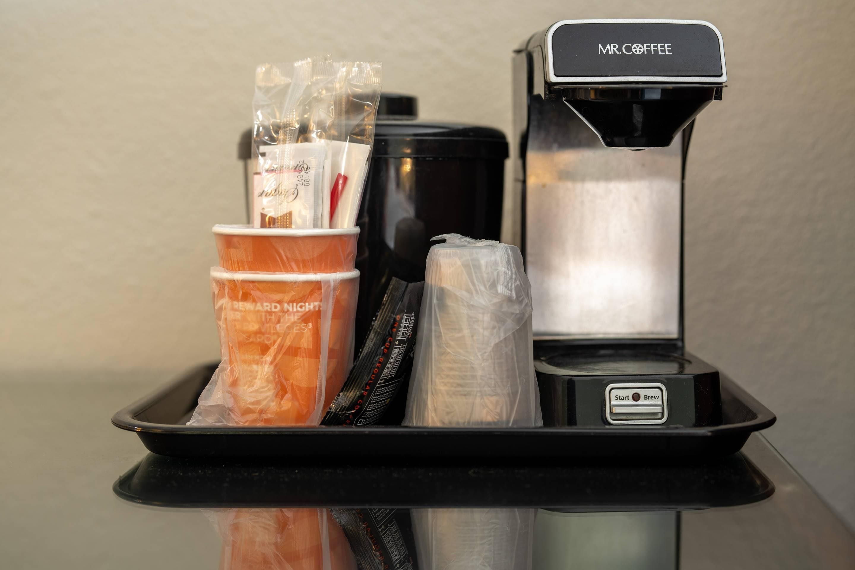 A coffee machine with a tray containing disposable cups and a coffee pod.