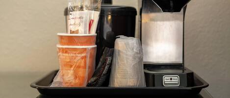A coffee machine with a tray containing disposable cups and a coffee pod.