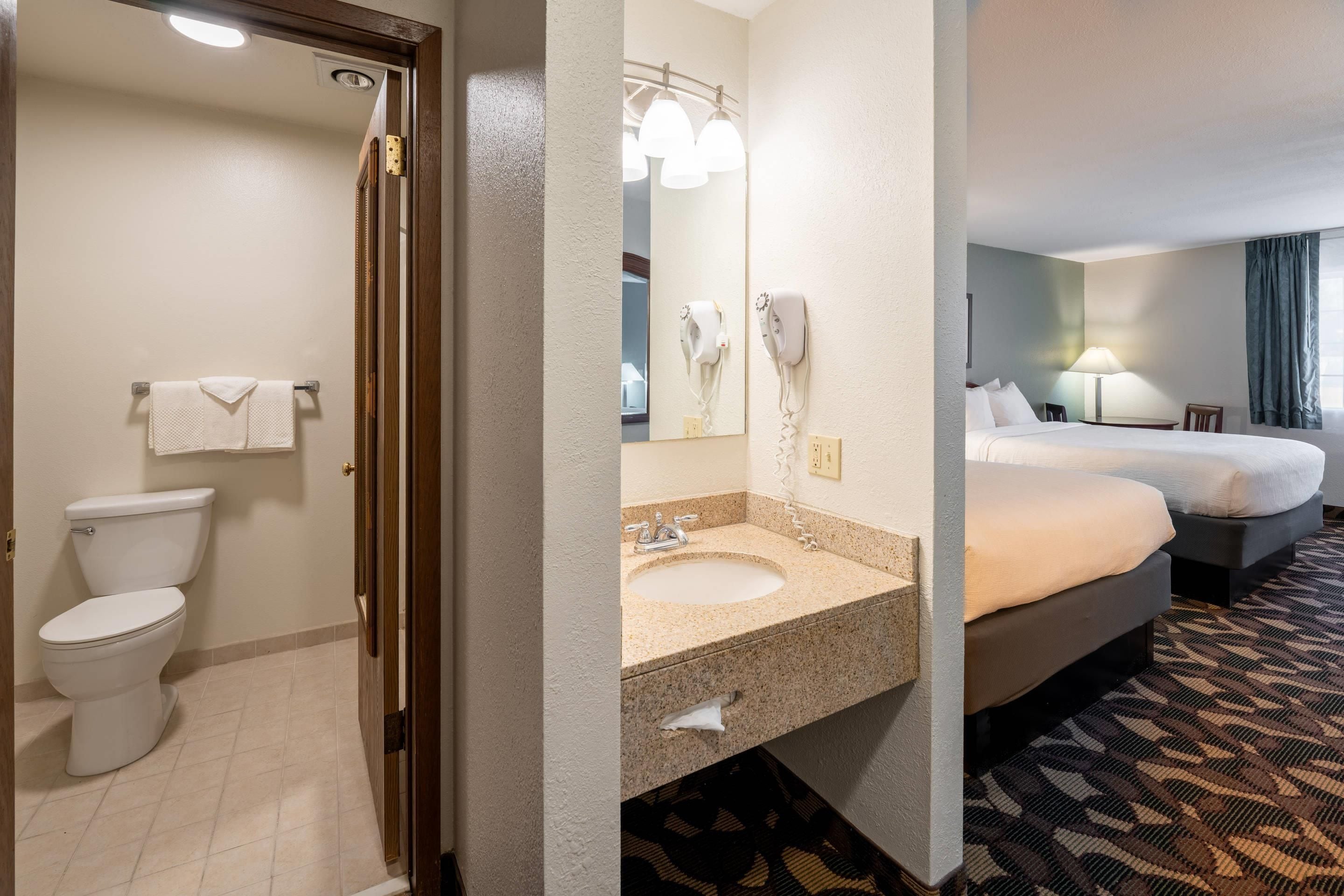 Un baño de hotel con inodoro, lavamanos y perchero para toallas.