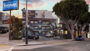 Un hotel Travelodge con una escalera que lleva a los pisos superiores, un estacionamiento y un árbol al frente.