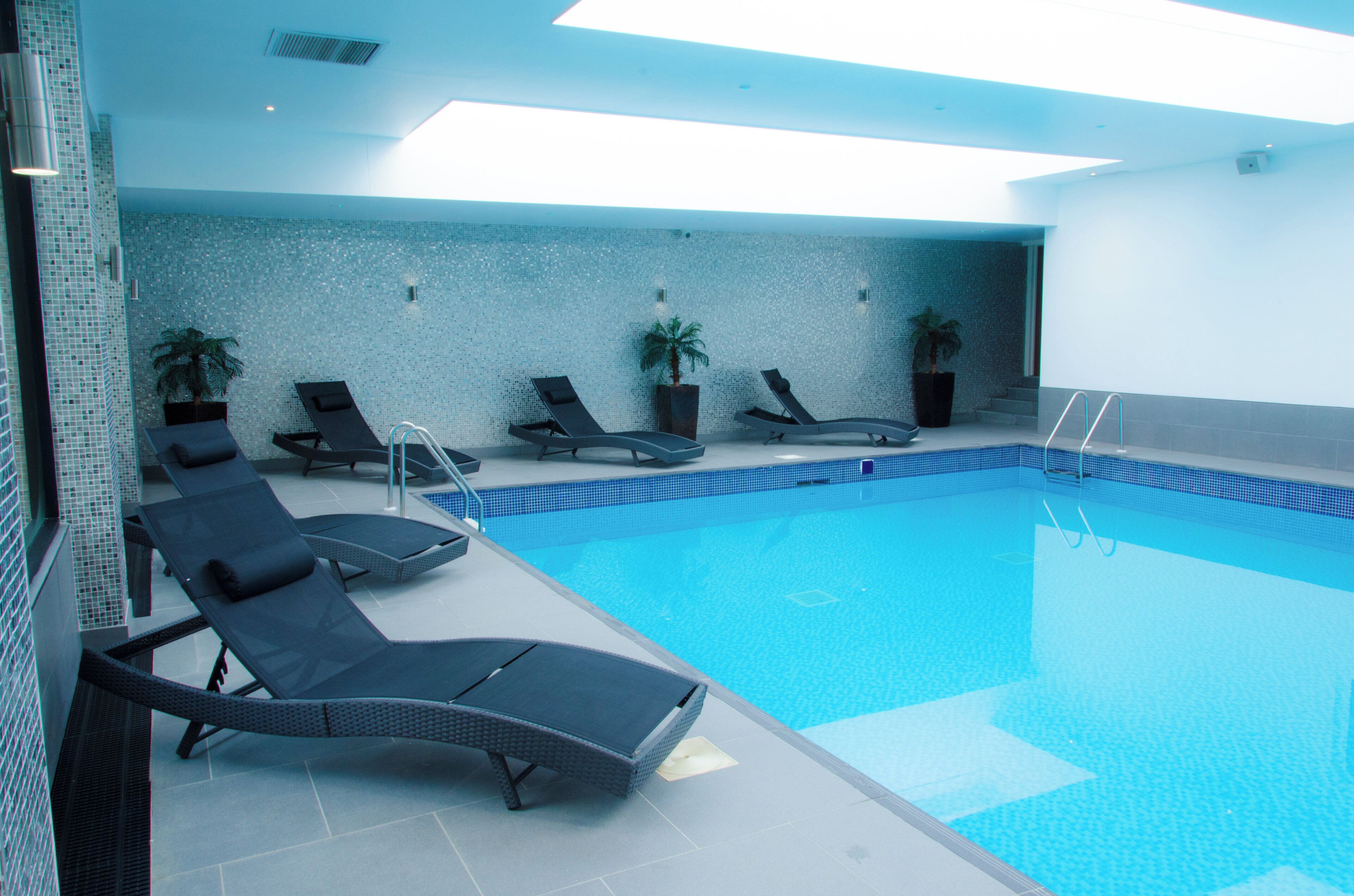 A swimming pool with lounge chairs and potted plants.