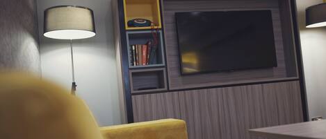 Ein modernes Zimmer mit Fernseher, Bücherregal und einem gelben Sessel.