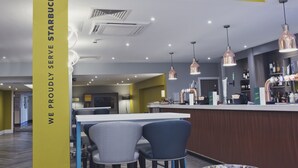 Decoração moderna com área de bar, assentos e um destaque para a placa da Starbucks.