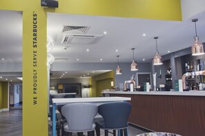 A modern interior with a bar area, seating, and a prominent Starbucks sign. - Holiday Inn Newcastle - Gosforth Park by IHG (Newcastle-upon-Tyne)