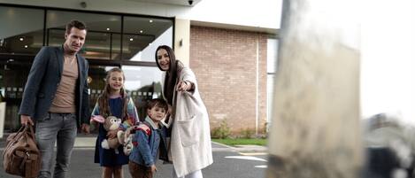 A family walking towards a building with a glass entrance.