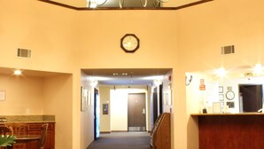 A hotel lobby with a chandelier, a reception desk, a clock, and a staircase. - Ocean Gateway Inn (Santa Paula)