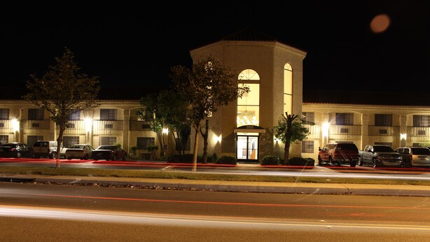A hotel with a central tower, multiple balconies, and a parking lot at night. - Ocean Gateway Inn (Santa Paula)