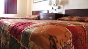 A bed with a patterned quilt and a wooden headboard. - Ocean Gateway Inn (Santa Paula)