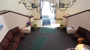 A lobby with two sofas, a small table, and potted plants. - Ocean Gateway Inn (Santa Paula)