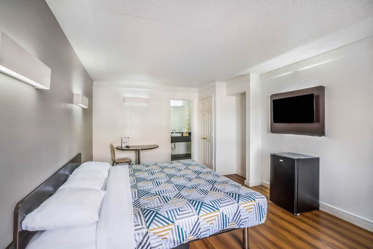 Een hotelkamer met een bed, een tafeltje, een televisie en een koelkast.