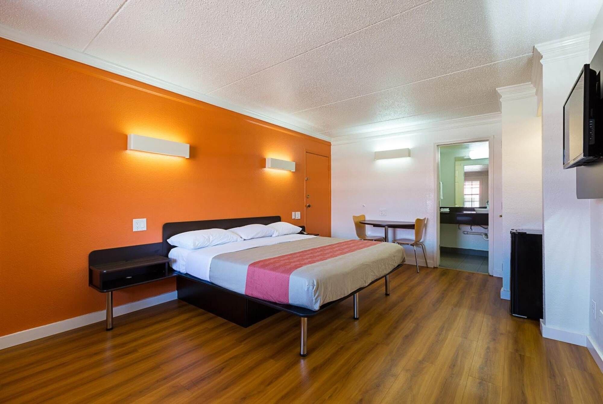 Una habitación de hotel con cama, mesitas de noche, escritorio y una silla.