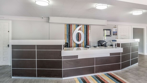A reception area with a large number '6' sign, a counter, and a striped rug. - Motel 6 Dallas, TX - Market Center (Dallas)