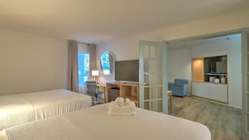 Habitación de hotel con dos camas, un escritorio con computadora, una silla y un televisor.