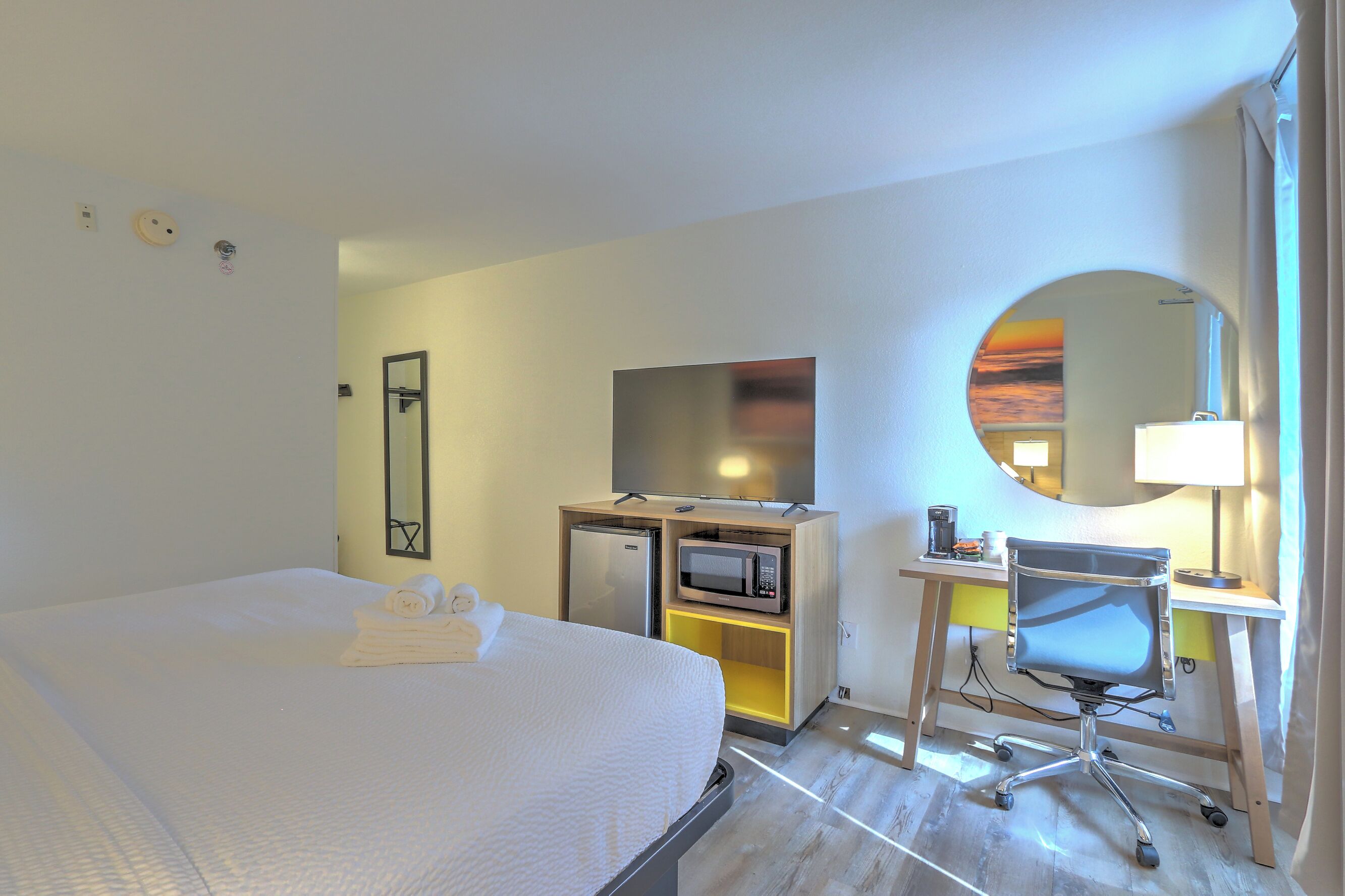 Una habitación de hotel con una cama, un escritorio con una computadora, un microondas y un televisor.