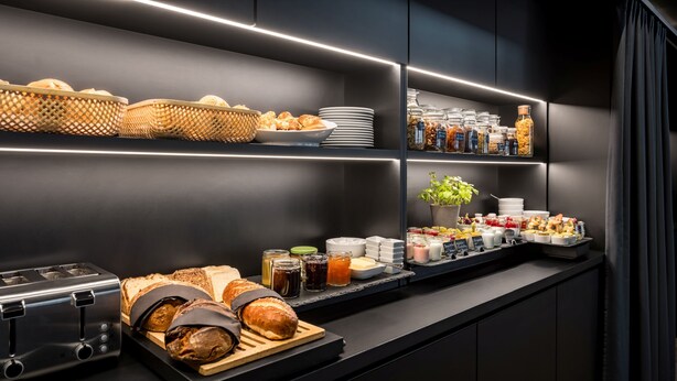 Um buffet de café da manhã moderno com diversos pães, doces e acompanhamentos.