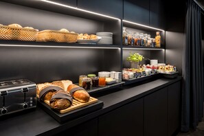 Un buffet de petit-déjeuner moderne proposant une variété de pains, de viennoiseries et d’accompagnements.