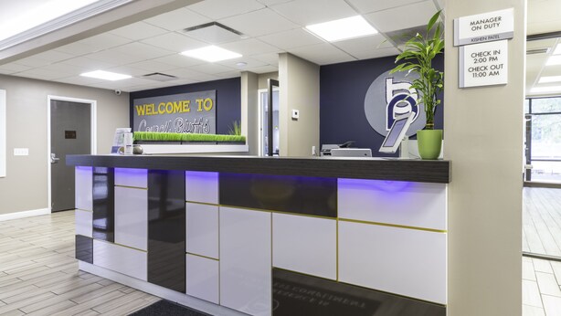Una mesa de recepción con un cartel que dice 'Welcome to Council Suites', un cartel que indica 'Manager on Duty' y un horario de registro de entrada y salida.