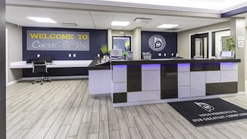 A reception area with a modern design, featuring a reception desk, a welcome sign, and a logo on the wall.
